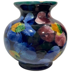Peut inclure: Un vase en céramique rond avec une couleur de base bleu marine foncé, orné d'un motif floral peint à la main dans des tons de bleu vif, magenta profond et jaune. Le vase présente un corps large et bulbeux, un col étroit et un bord évasé vert.