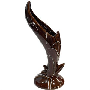 May include: A brown ceramic vase with a unique, curved design. The vase has a glossy finish with white crackle-style accents. The base is rounded, and the top flares out. A decorative piece for home decor.