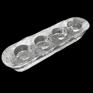 Può includere: Un portacandele in vetro trasparente e strutturato con quattro rientranze circolari. La forma oblunga ha un aspetto ruvido e ghiacciato, che suggerisce un'estetica artigianale o naturale. Il portacandele è progettato per contenere più candele.