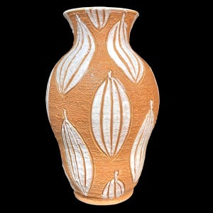 May include: A terracotta-colored ceramic vase with a textured surface and white leaf-like patterns. The vase has a wide body, a narrow neck, and a flared rim. The leaf designs are vertically oriented and evenly spaced around the vase.