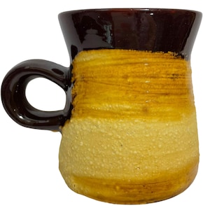 May include: A brown and yellow ceramic mug with a rounded handle. The mug has a dark brown top, a yellow middle section, and a light brown bottom.