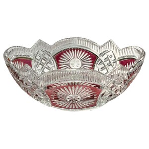 May include: A clear and cranberry red cut glass bowl featuring a scalloped rim and intricate geometric patterns. The exterior displays alternating panels of starburst motifs and cross-hatched designs, with vertical fluting along the upper edge.