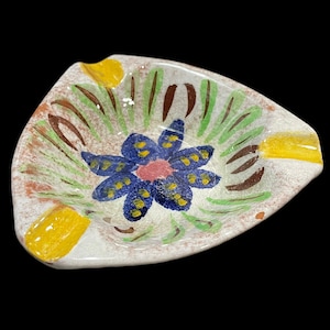 Puede incluir: Un cenicero de cerámica blanca con un diseño floral amarillo, verde, marrón, azul y rosa.