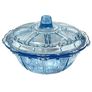 Peut inclure: Un bonbonnière en verre bleu clair avec un couvercle. Le plat a une forme ronde avec un bord perlé décoratif et un bouton sur le couvercle. Le verre est transparent avec une teinte bleu clair. Style vintage.