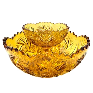 May include: A two-tiered amber glass serving dish with a scalloped edge and a starburst pattern. The dish is ideal for serving snacks, dips, or desserts.