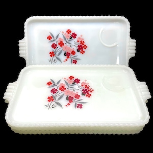 May include: A set of three white milk glass serving trays with a floral design featuring pink and red flowers. The trays have a raised beaded edge and a small indentation for a cup.