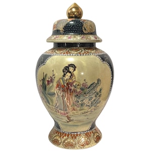 Peut inclure: Un pot à gingembre en céramique décoratif avec une finition dorée et une illustration centrale représentant deux personnages en tenue traditionnelle. Le pot possède un couvercle noir avec un fleuron doré, des motifs floraux et une base ornée de feuilles d'or.