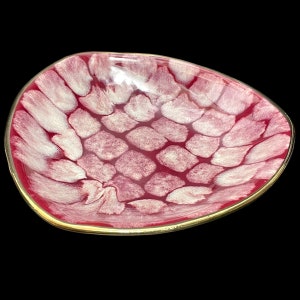 May include: A red and white ceramic serving dish with a gold rim. The dish has a unique pattern of white swirls on a red background.