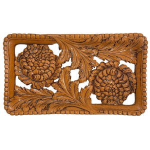 May include: A rectangular wooden tray with carved floral and leaf designs. The tray features two large, detailed flower carvings and intricate leaf patterns. The frame has a beaded edge, and the wood has a warm, brown tone.