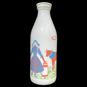 Op de afbeelding: Witte melkfles met een kleurrijke illustratie van een meisje, een koe en een melkkan. Het meisje draagt een blauwe jurk met oranje strepen. De koe is oranje met een blauwe nek. De fles heeft een witte dop.