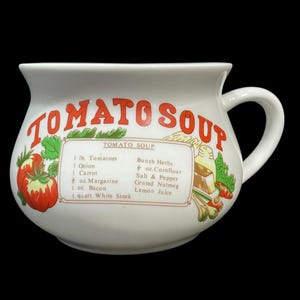 May include: White ceramic tomato soup mug with a handle. The mug features the words "TOMATO SOUP" in red, along with a recipe for tomato soup. The recipe includes ingredients like tomatoes, onion, and herbs. A colorful illustration of tomatoes and vegetables is also present.