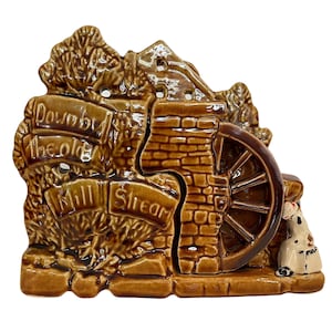 Puede incluir: Colgante de pared de cerámica marrón que representa un molino de agua con un letrero que dice "Down by the old Mill Stream".