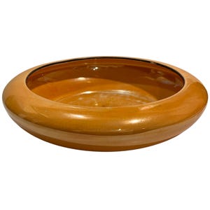 May include: A round, low-profile ceramic bowl with a glossy, vibrant orange glaze. The bowl features a wide, smooth, rounded rim that curves inward towards the centre, creating a shallow basin with a uniform, reflective surface finish throughout.