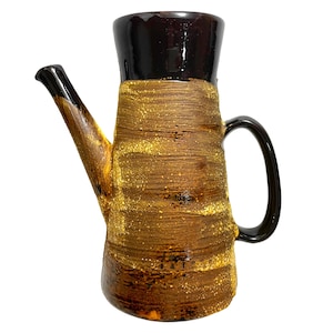 May include: A brown and black ceramic pitcher with a textured surface and a gold glaze. The pitcher has a spout and a handle.
