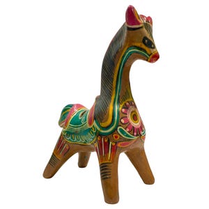 Peut inclure: Figurine de cheval d'art populaire peinte à la main. Le cheval brun a un long cou et est décoré de motifs floraux et géométriques colorés en rose, vert, jaune et rouge. La figurine repose sur quatre pattes.