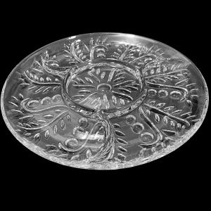 Pode incluir: Travessa de servir em vidro transparente com uma tigela central para molhos e quatro secções circundantes. A travessa apresenta um design floral e de folhas em relevo. A travessa redonda é ideal para servir aperitivos ou petiscos.