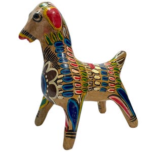 Könnte beinhalten: Eine handbemalte Keramikfigur eines Ziegenbocks mit einem Farbschema in Braun, Weiß, Blau, Grün, Rot und Gelb. Der Ziegenbock steht auf allen vieren und hat einen verspielten, volkstümlichen Stil.