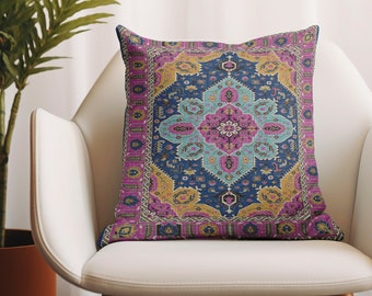 May include: A decorative throw pillow with a colorful, intricate pattern reminiscent of a Persian rug. The pillow features a central design with shades of pink, blue, and yellow, surrounded by a border of gold and purple.