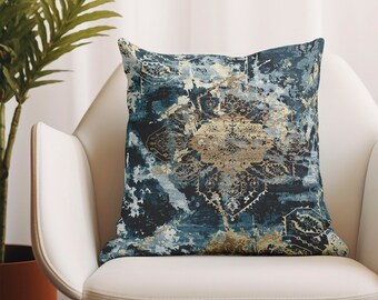 May include: A blue and gold patterned throw pillow with a distressed, vintage look. The pillow is sitting on a white armchair with wooden legs.