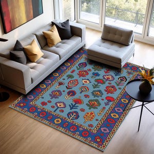 May include: A rectangular area rug with a light blue background and a floral pattern in red, yellow, green, and purple. The rug has a dark blue border with a repeating geometric design. The rug is placed in a living room setting.