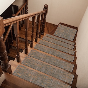 Könnte beinhalten: Ein Satz von sechs rutschfesten Treppenstufen mit einem grauen und goldenen Muster. Die Stufen sind auf einer Holztreppe mit einem Holzgeländer angebracht.