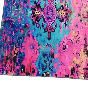 a vibrant, colorful, and intricate pattern with a mix of pink, blue, and black hues. The pattern appears to be a textile or rug with a floral or abstract design, and it is spread across the frame.