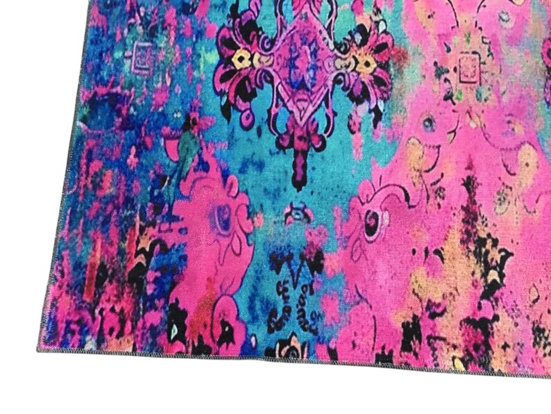a vibrant, colorful, and intricate pattern with a mix of pink, blue, and black hues. The pattern appears to be a textile or rug with a floral or abstract design, and it is spread across the frame.