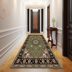 A hallway with a large, ornate rug on the floor, leading to a door with a chandelier above it. The hallway is decorated with a wooden table and a plant, creating a warm and inviting atmosphere.