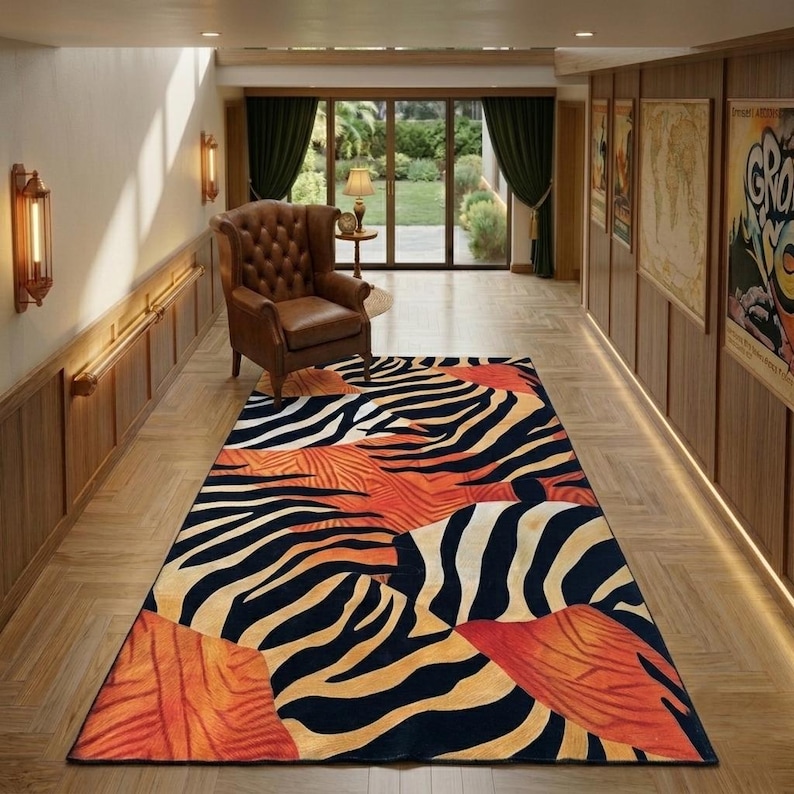 a hallway with a large rug featuring a zebra print design in black, white, and orange colors. The rug is placed on a wooden floor, and there is a leather armchair in the background. The hallway also has a sliding glass door and wooden paneling on the walls.