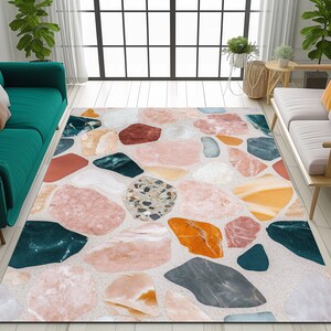 May include: A colourful area rug with a geometric pattern of various sized, irregularly shaped, multi-coloured stones on a white background.