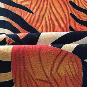 a close-up view of a vibrant, abstract rug with a striking pattern of orange, black, and white stripes and swirls.