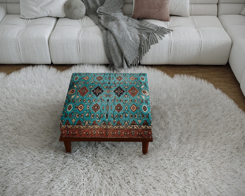 a cozy living room with a plush white rug, a white sofa, and a colorful patterned ottoman in the center of the room.