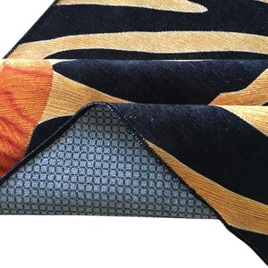 a close-up view of a colorful rug with a geometric pattern in shades of orange, black, and gray.
