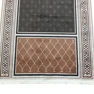 a rug with a geometric pattern and a darker geometric pattern on the lower half.