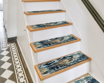May include: A set of five non-slip stair treads with a blue, gold, and brown abstract pattern. The treads are placed on wooden stairs with white risers.