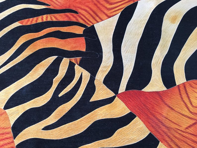 The image is a close-up of a textured surface with a striking pattern of black, orange, and white stripes and lines.