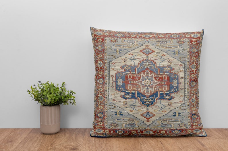 Puede incluir: Una almohada decorativa con un dise&ntilde;o estampado en azul, rojo y crema. El patr&oacute;n recuerda a una alfombra tradicional.