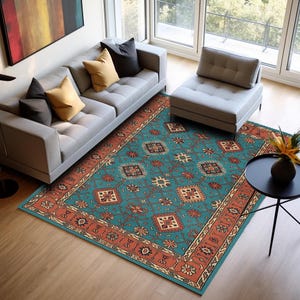 Peut inclure: Un tapis de sol turquoise avec un motif géométrique détaillé et une bordure de couleur rouille. Le tapis est placé dans un salon, avec un canapé gris, des coussins et une petite table d'appoint noire.