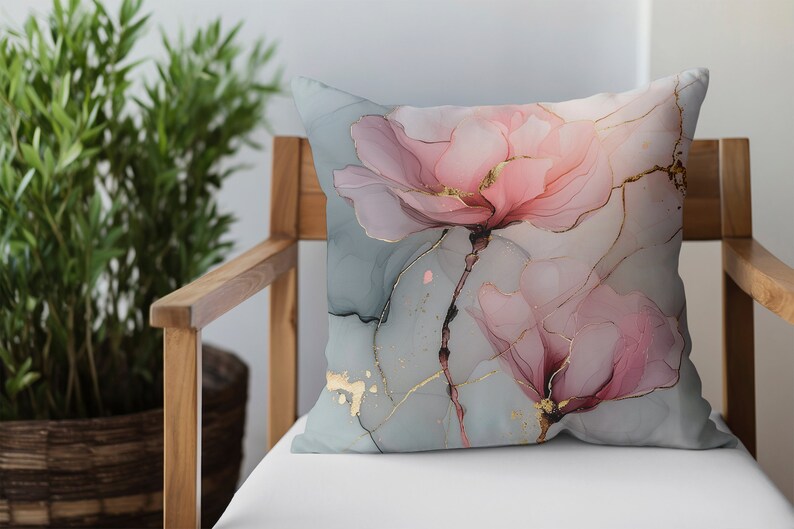 May include: A decorative throw pillow with a floral design. The pillow features two pink flowers with gold accents on a light blue background.