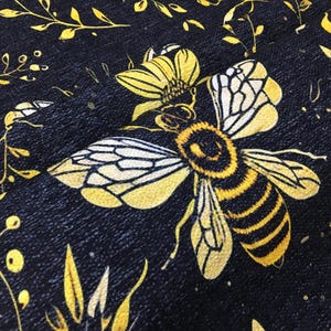 a close-up view of a detailed, colorful print of a bee on a black background.