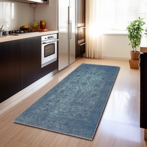 May include: A blue and green distressed runner rug with a faded floral pattern. The rug is placed in a kitchen with hardwood floors.