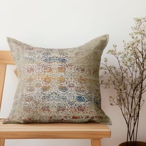 Peut inclure: Un coussin décoratif avec un motif abstrait coloré dans des tons de bleu, orange et marron. Le coussin est posé sur une chaise en bois.