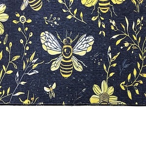 a close-up view of a black fabric with a repeating pattern of yellow flowers and bees.
