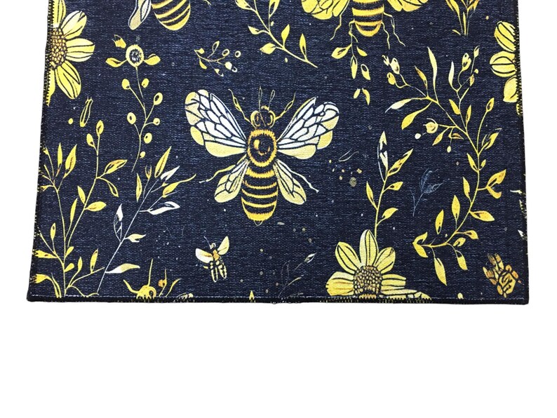 a close-up view of a black fabric with a repeating pattern of yellow flowers and bees.