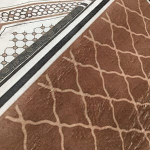 a close-up view of a brown and white patterned fabric or carpet, with a geometric design featuring a repeating diamond pattern.