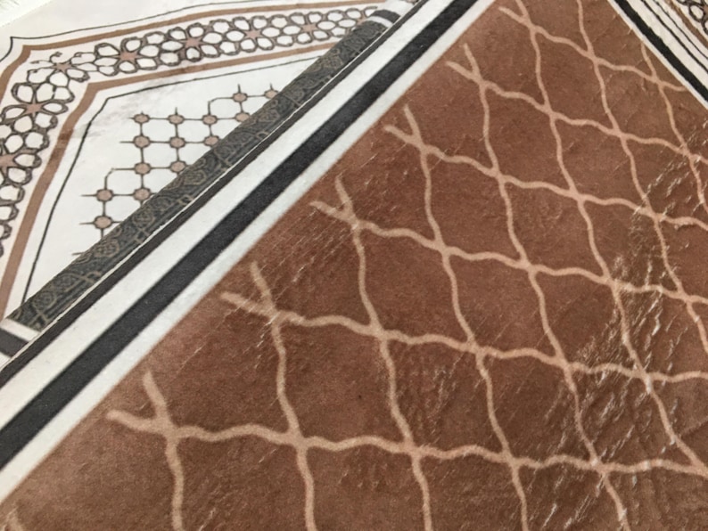 a close-up view of a brown and white patterned fabric or carpet, with a geometric design featuring a repeating diamond pattern.