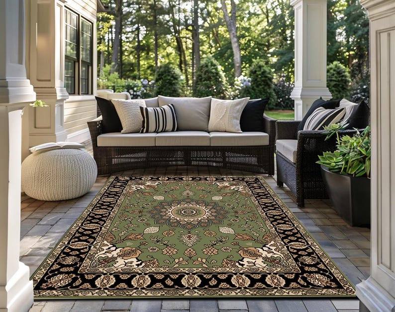 a well-furnished outdoor living area with a large rug on the floor, a comfortable sofa, and wicker furniture. The area is surrounded by lush greenery, creating a serene and inviting atmosphere.