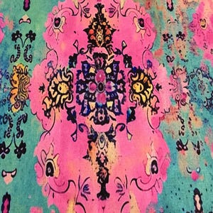 The image is a vibrant and intricate textile with a floral pattern in shades of pink, blue, and green. The design features a central motif surrounded by smaller floral and geometric elements, creating a visually striking and detailed composition.