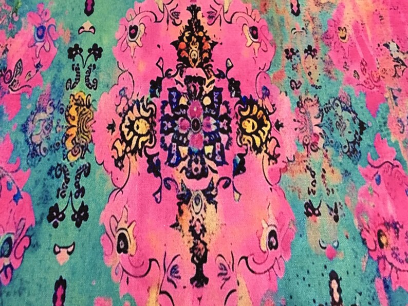 The image is a vibrant and intricate textile with a floral pattern in shades of pink, blue, and green. The design features a central motif surrounded by smaller floral and geometric elements, creating a visually striking and detailed composition.