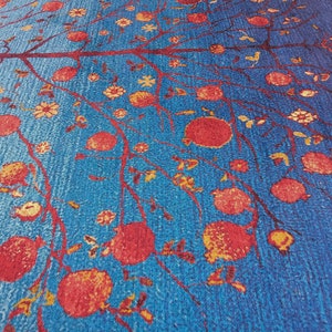 May include: A blue rug with a repeating pattern of a tree with red pomegranates and small yellow flowers.